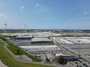 Luftaufnahme bei schönem Wetter vom Gelände der Anker Schiffahrt in Emden auf dem das Bürogebäude, Lagerhallen, Windräder sowie die große Fläche des Automobilumschlagplatzes mit unzähligen Autos zu sehen sind.